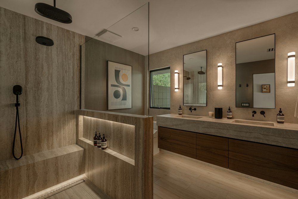Badkamer met inloopdouche, houten wandbekleding en een zwevend meubel met twee lavabo's