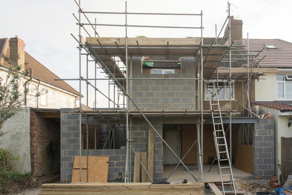 Bakstenen rijwoning in verbouwing, met een stelling rond de nieuwe aanbouw achteraan