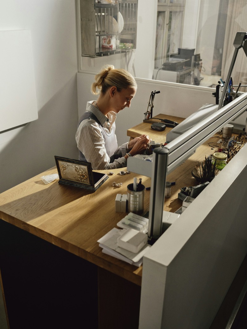 Juweelontwerpster aan het werk aan haar werkbank in een licht atelier