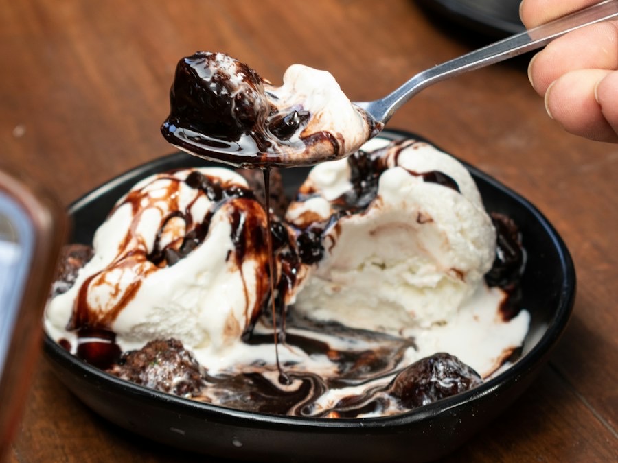 Vanilleroomijs met warme chocoladesaus in een donker schaaltje
