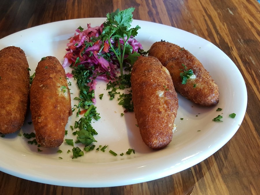 Goudbruine kroketten met verse peterselie op een wit bord
