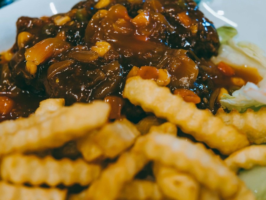 Stoofvlees in donkere saus met frietjes op een bord