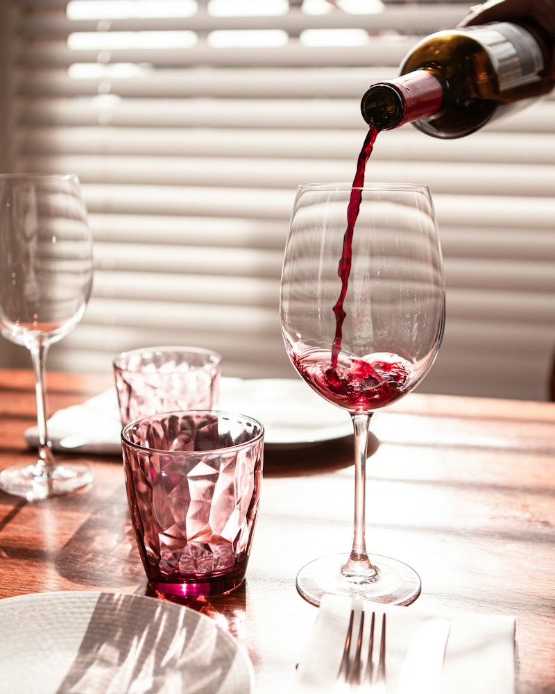 Rode wijn wordt in een glas geschonken aan een gedekte tafel